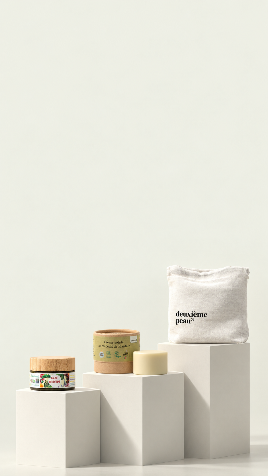 Baume L’Endormi, crème solide au plantain et textile Deuxième Peau présentés sur des socles crème